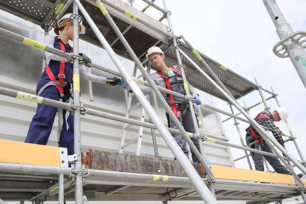 Construction Workers Installing Scaffolding On Site